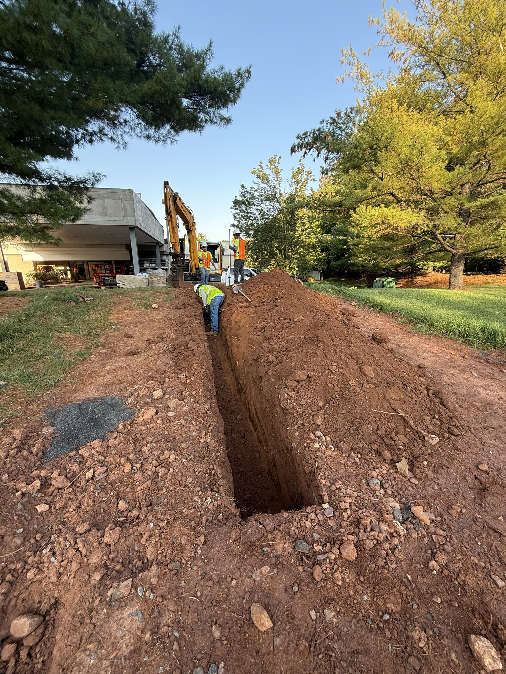 Excavation crew digging a deep utility trench with an excavator in Glenside, PA