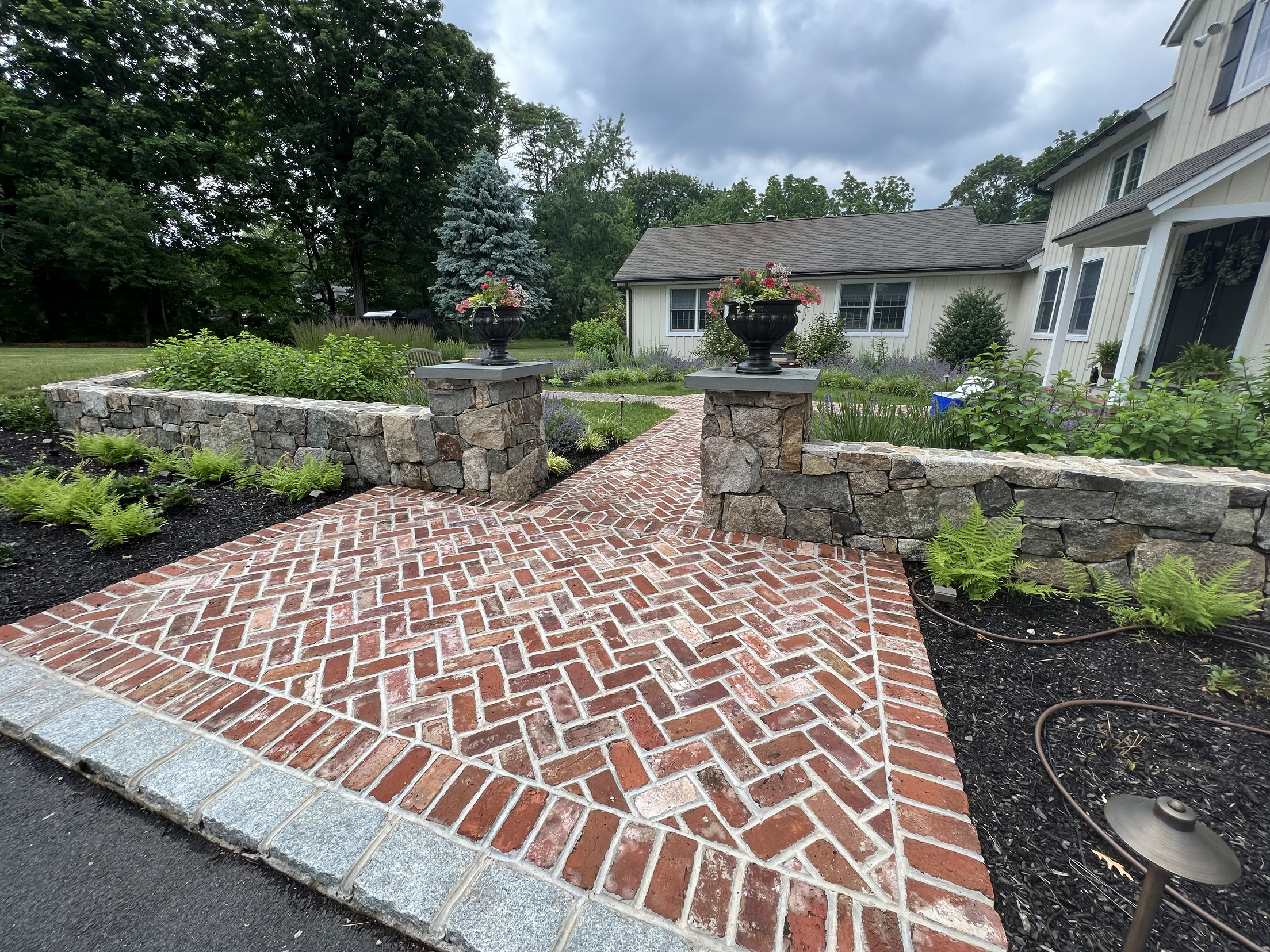 Herringbone reclaimed brick walkway with a granite border and stone pillars in Glenside, PA