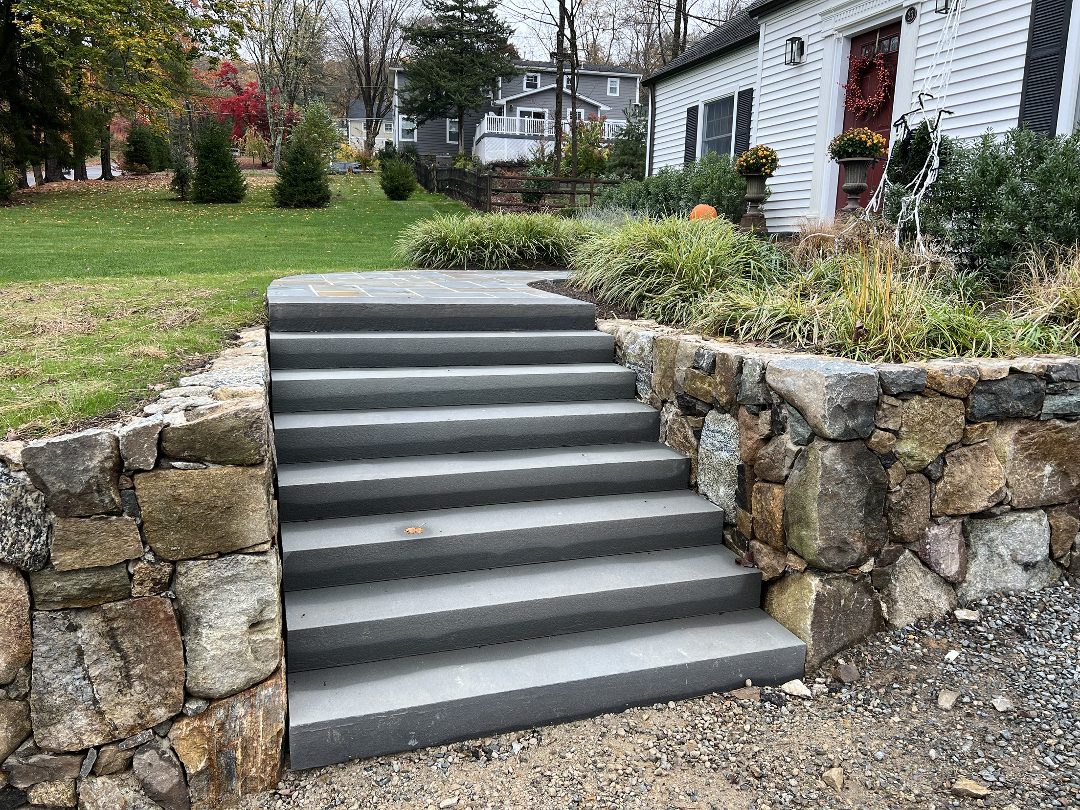 Bluestone steps flanked by a natural stone retaining wall and ornamental grasses at a Montgomery County, PA home
